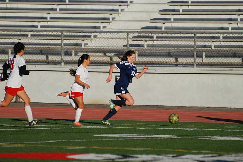 Sophomore forward Megan Cavender (22) dribbles the ball with defenders in chase